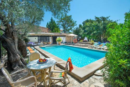 a swimming pool with a table and chairs next to a house at Owl Booking Villa Rafals - Wonder in the Midst of Nature in Pollença