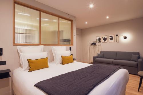 a bedroom with a large white bed and a couch at Tinah Paris, Champs Elysées in Paris