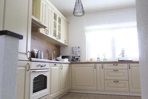 a kitchen with white cabinets and a window at Kuća za odmor ANA in Kupres