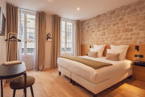 a hotel room with a bed and a table and window at Tinah Paris, Champs Elysées in Paris