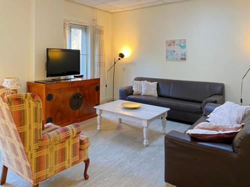 a living room with a couch and a tv at Landgoed Huize Glory in Bergen aan Zee