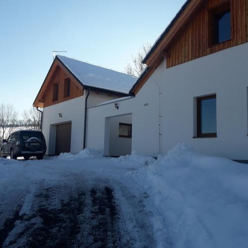 a house with a car parked in the snow at apartman u\Kapra in Jeřmanice