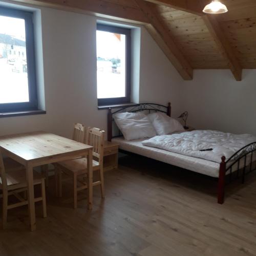 a bedroom with a bed and a table and windows at apartman u\Kapra in Jeřmanice