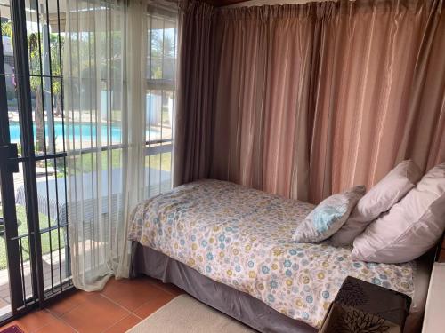 a bedroom with a bed and a balcony with a pool at Arum Field Accommodation in Table View