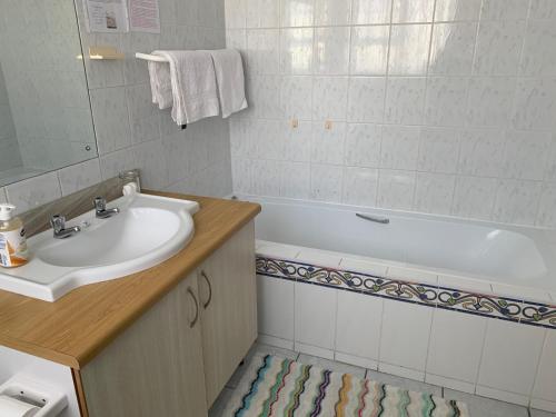 een badkamer met een wastafel en een bad bij Arum Field Accommodation in Table View