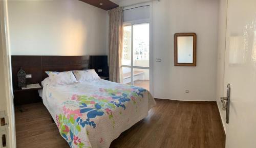Un dormitorio con una cama y un espejo y una ventana. en Duplex vu sur mer, en Martil