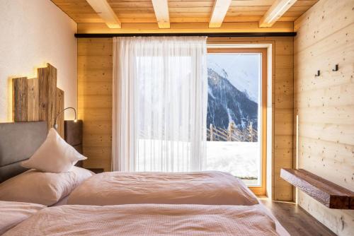 a bedroom with a bed and a large window at Chalet Henne- Hochgruberhof in Selva dei Molini