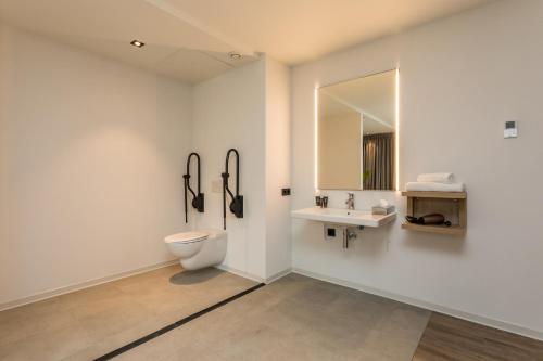 a bathroom with a toilet and a sink and a mirror at Hotel de Rousch - 4 sterren Superieur in Heerlen