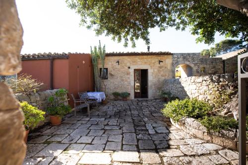 a stone walkway leading to a house with a stone wall at IzzHome Carrubo in Santa Croce Camerina