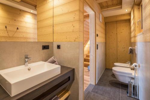 two images of a bathroom with a sink and a toilet at Chalets Reisnock - Hochgruberhof in Selva dei Molini