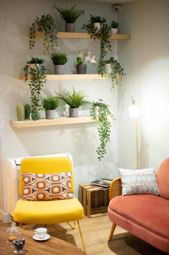 a living room with a yellow chair and plants on shelves at 5 Chambres en Ville in Clermont-Ferrand