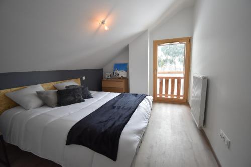 Un dormitorio con una cama grande y una ventana en VAUJANYLOCATIONS - Le Chalet d Antoine et Mary, en Vaujany