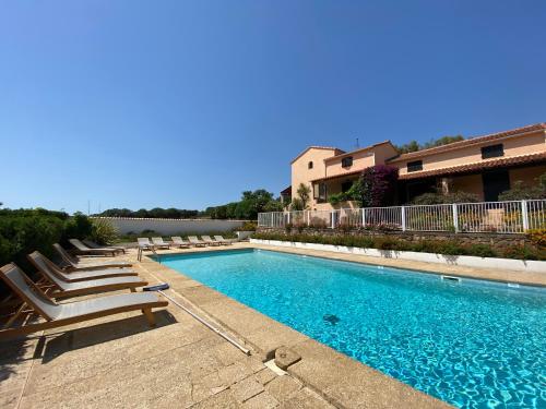 une piscine avec des chaises longues et un bâtiment dans l'établissement Résidence Marie Diane - Appart Coté Piscine F, à Propriano