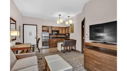 a living room with a large television and a kitchen at Staybridge Suites Salt Lake-West Valley City by IHG in West Valley City