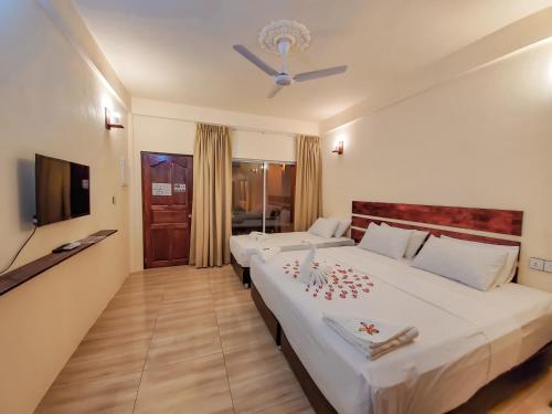 Habitación de hotel con 2 camas y TV en Shoreline Grand, en Thoddoo