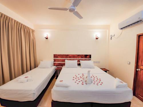 Habitación de hotel con 2 camas y ventilador de techo. en Shoreline Grand, en Thoddoo