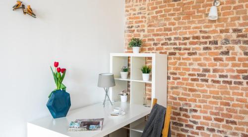 a white desk with flowers on it next to a brick wall at 7 Koron - Exclusive Apartments in Kraków