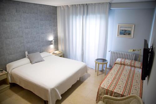 a hotel room with a white bed and a chair at Hotel Reina Victoria in Hellín