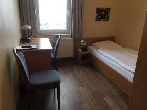 a bedroom with a bed and a desk and a chair at Hotel Kieler Förde in Kiel