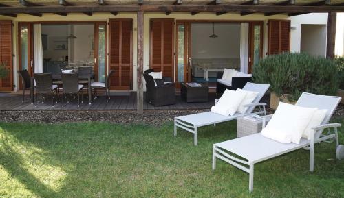a patio with white chairs and a table on a deck at Is Arenas Private Golf Foresterie - Unlimited golf included in Narbolia