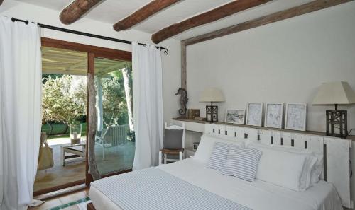 a bedroom with a white bed and a sliding glass door at Is Arenas Private Golf Foresterie - Unlimited golf included in Narbolia