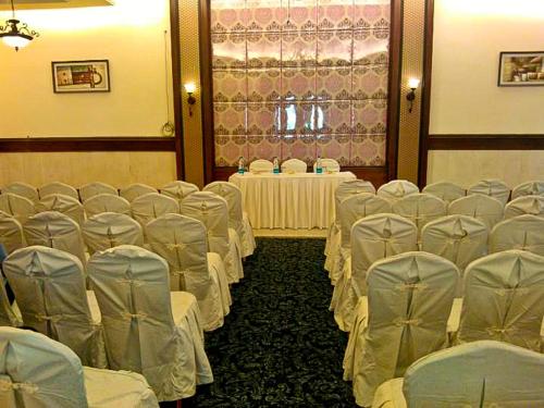 a room with rows of chairs and tables with whiteitures at Pramod Convention & Club Resort in Cuttack