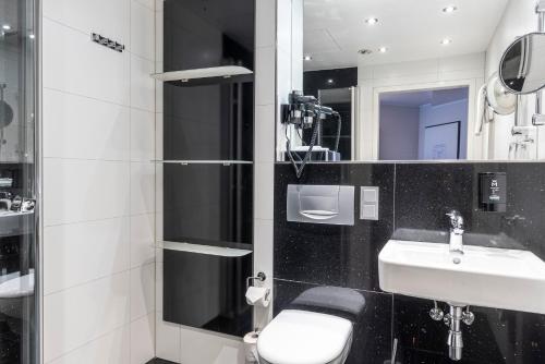 a bathroom with a white toilet and a sink at Mauritius Hotel & Therme in Cologne