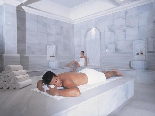 a man laying in a bath tub with a woman in the background at Dan Jerusalem Hotel in Jerusalem