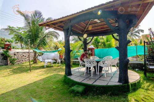 a man sitting at a table under a gazebo at Malhar Villa -Kashid in Kashid