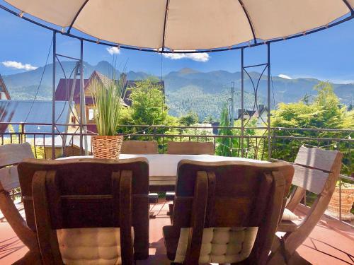 a table and chairs on a balcony with an umbrella at Straszny Dwór in Zakopane