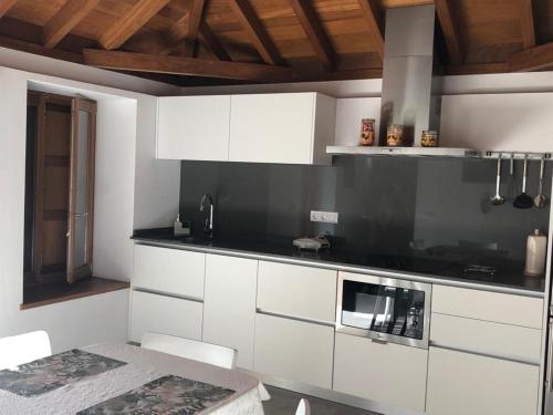 eine Küche mit weißen Schränken und einer schwarzen Arbeitsplatte in der Unterkunft Casa Rural El Horno Masca in Buenavista del Norte