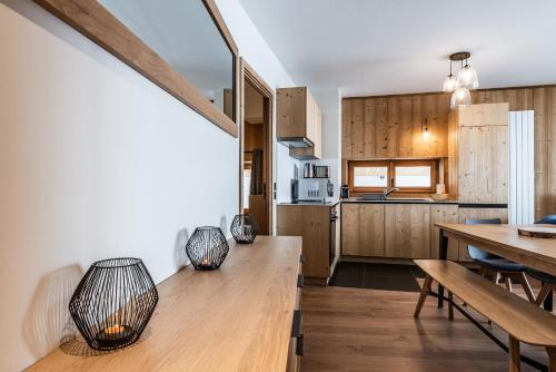 a kitchen and dining room with wooden cabinets and a table at Residence Hameau de Clotaire Alpe d'Huez - by EMERALD STAY in L'Alpe-d'Huez