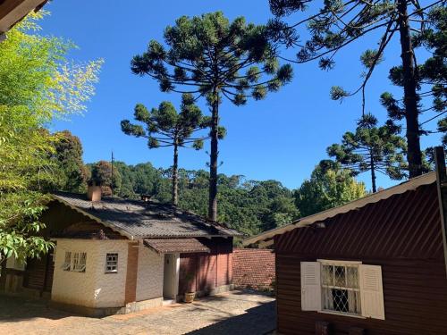 an old house and a barn with trees in the background at Chalé Terrazza in Campos do Jordão