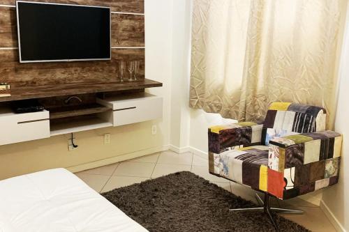 uma sala de estar com uma televisão e uma cadeira em Apto lindo e aconchegante próximo a praia em Itapema