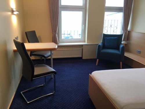 a room with a bed and a desk and two chairs at Hotel Kieler Förde in Kiel