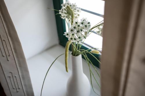 a white vase with flowers sitting on a window sill at Pri Žabarju Bed & Breakfast Ljubljana in Ljubljana