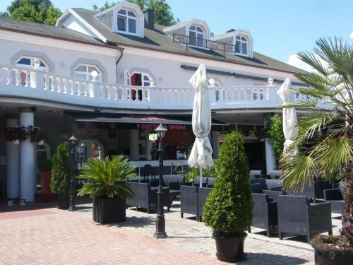un restaurante con sillas y sombrillas frente a un edificio en Y Panzió, en Balatonlelle
