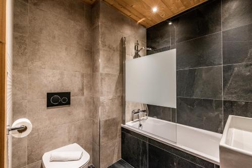 a bathroom with a tub and a toilet and a sink at Residence Hameau de Clotaire Alpe d'Huez - by EMERALD STAY in L'Alpe-d'Huez