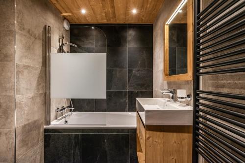 a bathroom with a tub and a sink at Residence Hameau de Clotaire Alpe d'Huez - by EMERALD STAY in L'Alpe-d'Huez