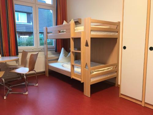 a bunk bed in a room with a desk and a chair at Jugendherberge Heide in Heide