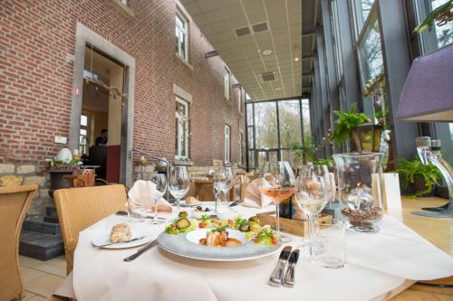 a table with a plate of food and wine glasses at Hotel de Rousch in Heerlen