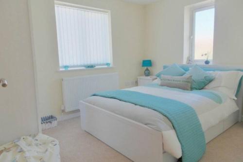 a white bedroom with a bed with a blue blanket at SEABREEZE in Kent
