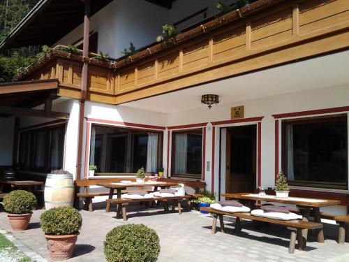 a patio with wooden tables and benches and windows at Biogasthaus Plonerhof in Bressanone