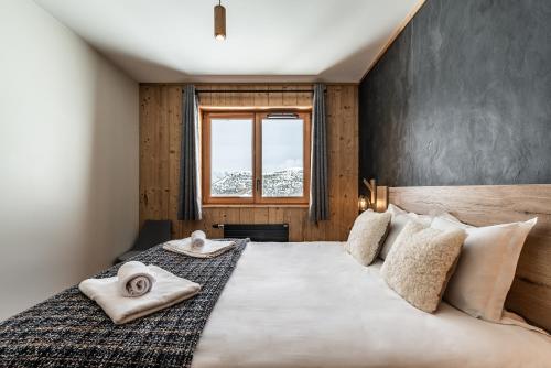 a bedroom with a large bed with a window at Residence Hameau de Clotaire Alpe d'Huez - by EMERALD STAY in L'Alpe-d'Huez