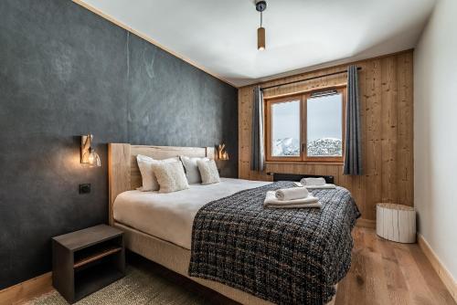 a bedroom with a large bed and a window at Residence Hameau de Clotaire Alpe d'Huez - by EMERALD STAY in L'Alpe-d'Huez