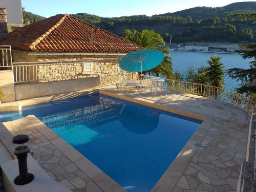 una piscina con sombrilla junto a una casa en Villa Aquamare****, en Vela Luka