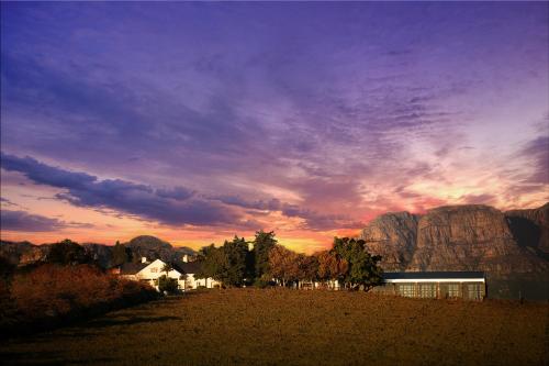 a building in a field with a sunset in the background at Bakenhof Winelands Lodge in Paarl