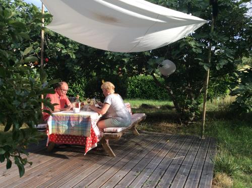 two people sitting at a table under an umbrella at Puechblanc Gîtes et Chambre d'hôte dans le Triangle d'or Gaillac-Albi-Cordes sur Ciel in Fayssac