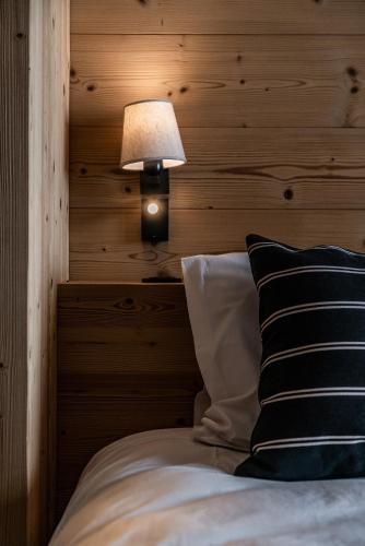 a bed with a lamp next to a wooden wall at Apartment Wapa Alpe d'Huez - by EMERALD STAY in L'Alpe-d'Huez