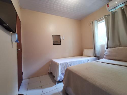 Una pequeña habitación con dos camas y una ventana. en Casa do Anjo, en Fernando de Noronha